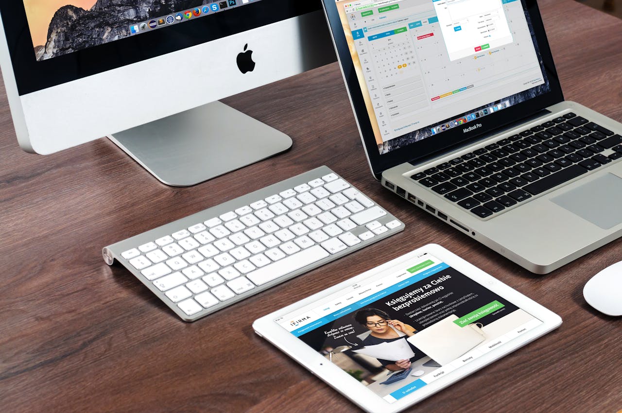 why-choose-us A sleek office desk setup featuring Apple devices: iMac, MacBook, and iPad.