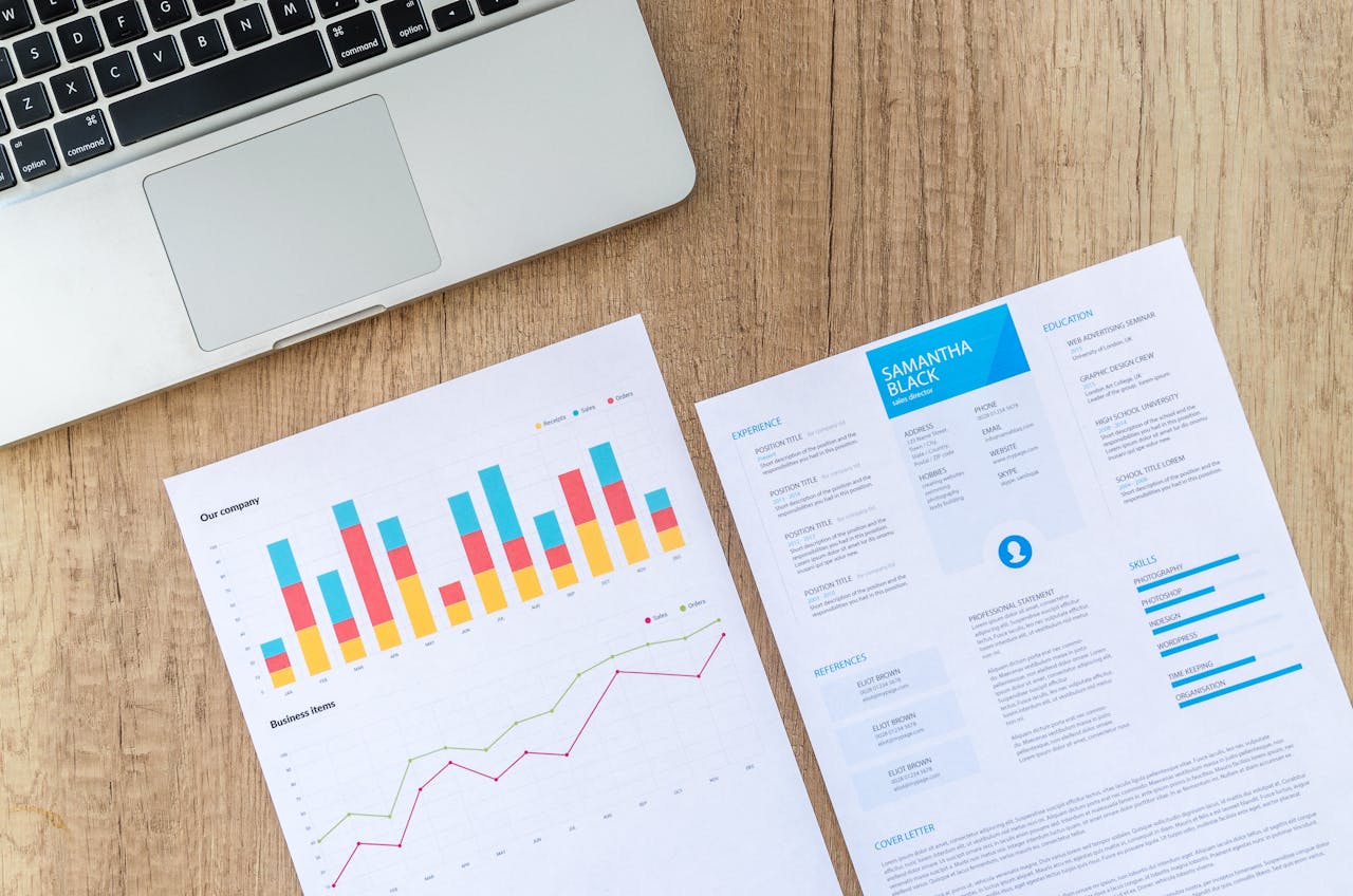 Crafting Captivating Headlines: Your awesome post title goes here Top view of a laptop, charts, and resume on a wooden desk, showcasing business analysis and job application.